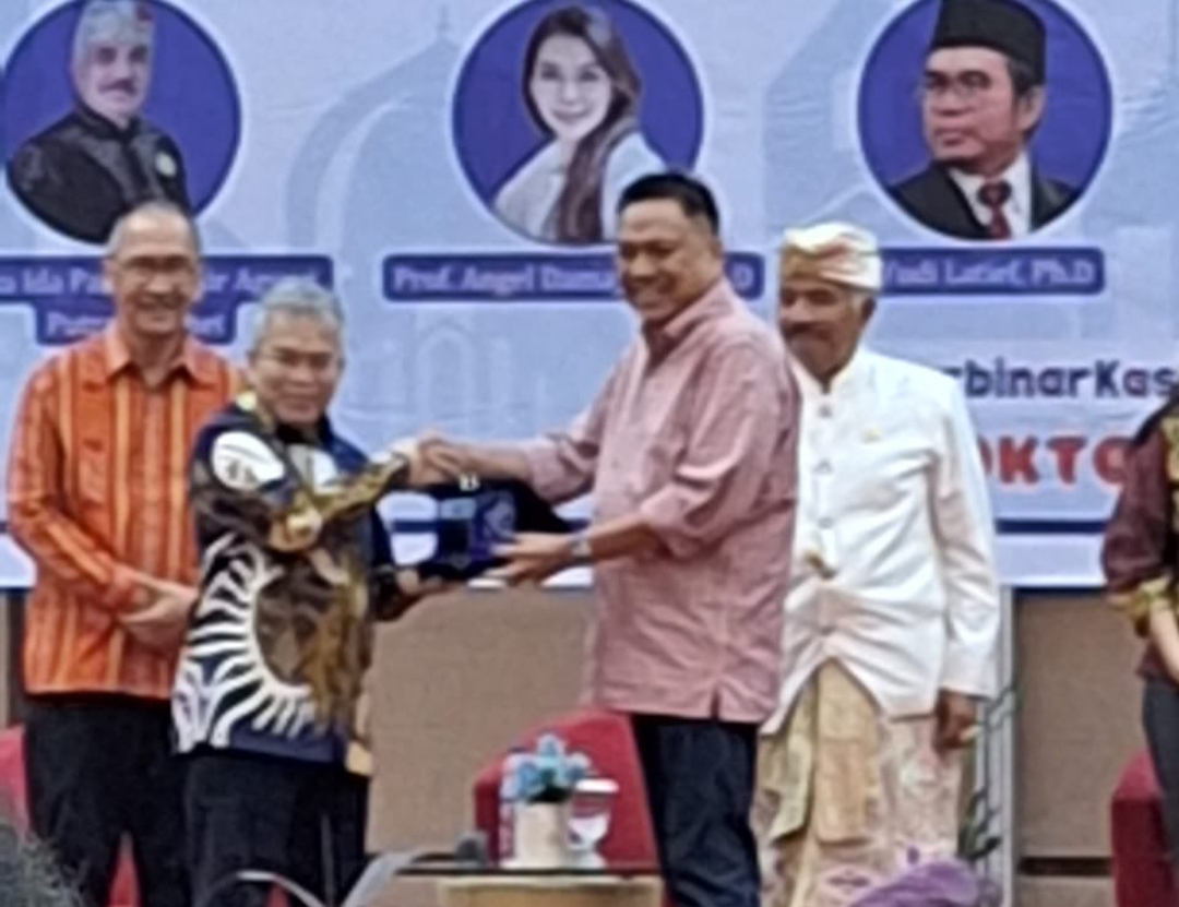 Prof Olly Dondokanbey saat menyerahkan cendera mata kepada  salah satu pembicara  Yudi Latief, Ph.D
