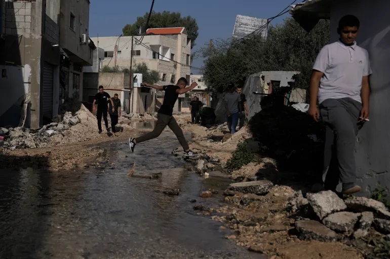 Warga Palestina berjalan melalui jalan yang hancur akibat serangan tentara Israel di Jenin, Tepi Barat (Majdi Mohammed/AP Photo)