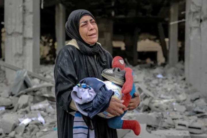 Perempuan Palestina memegang mainan dan sepatu anak-anak setelah serangan Israel di lingkungan Remal di Kota Gaza pada Sabtu (16/3) (AFP)