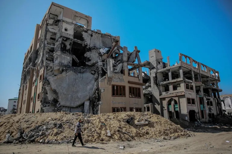 Seorang warga Palestina berjalan melewati Universitas Islam yang rusak parah di Kota Gaza (AFP)