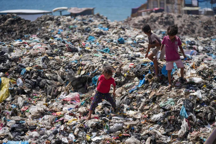 Anak-anak Palestina mencari melalui gundukan sampah yang membusuk di kamp pengungsi Nuseirat, Jalur Gaza, pada 20 Juni (Abdel Kareem Hana/AP Photo)