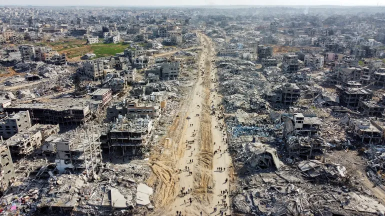 Pemandangan udara menunjukkan warga Palestina berjalan melewati puing-puing rumah dan bangunan yang hancur di Jabalia di Jalur Gaza utara, pada 19 Januari 2025 (Mahmoud Al-Basos/Reuters)