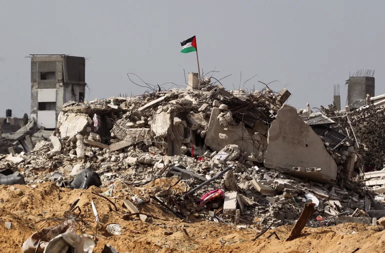 Bendera Palestina berkibar di antara reruntuhan bangunan di Rafah, Jalur Gaza selatan (Hatem Khaled/Reuters)