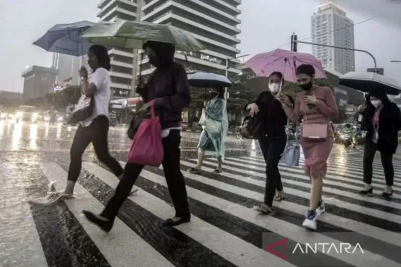 Ilustrasi, Sejumlah karyawati menyeberangi jalan yang tergenang air di depan gedung perkantoran saat hujan ringan.