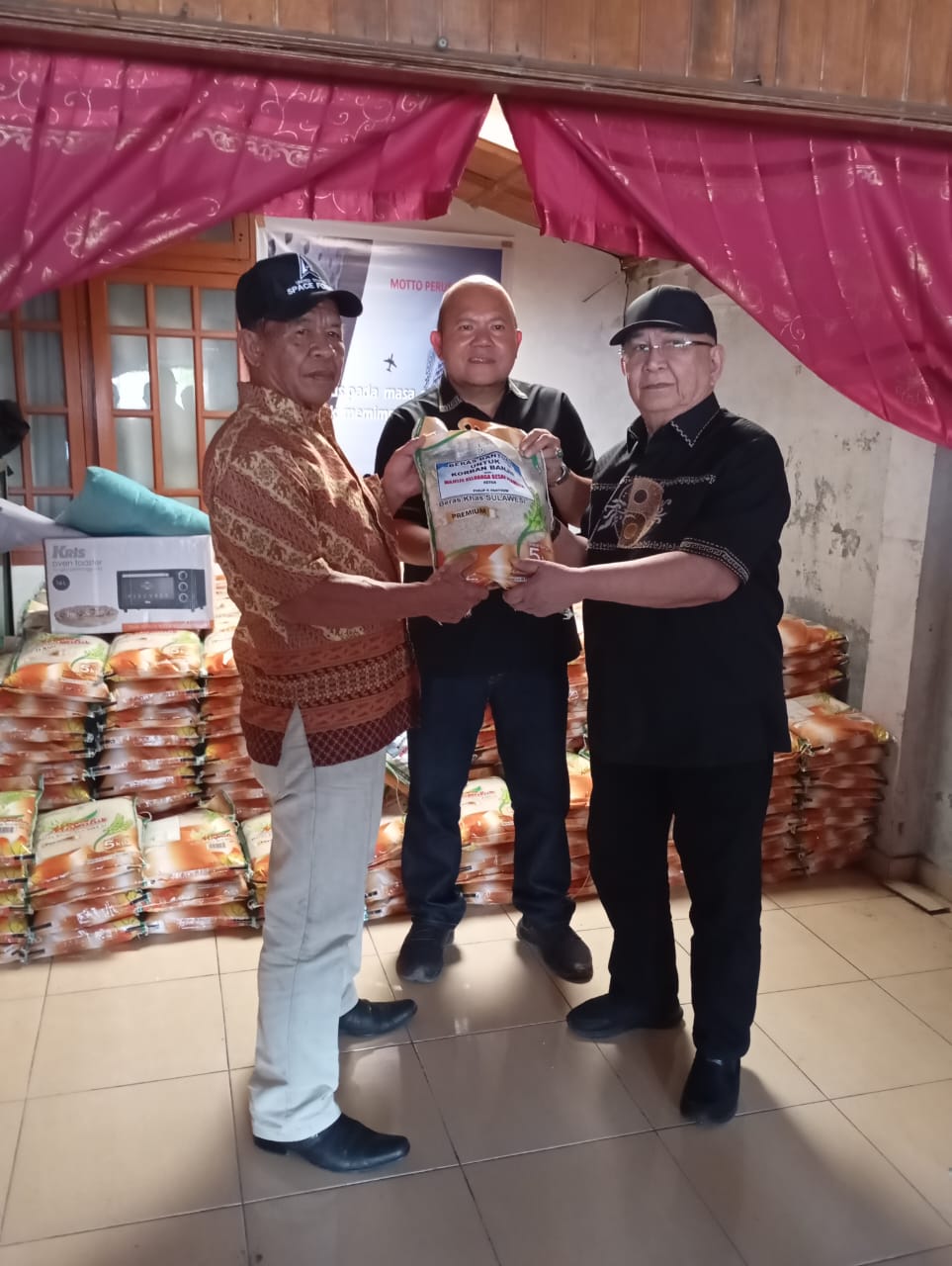 Ketua Majelis Keluarga Besar Permesta, Philip Pantouw (kanan), secara simbolis menyerahkan bantuan beras kepada warga terdampak banjir di sekitar Danau Tondano, Minahasa.