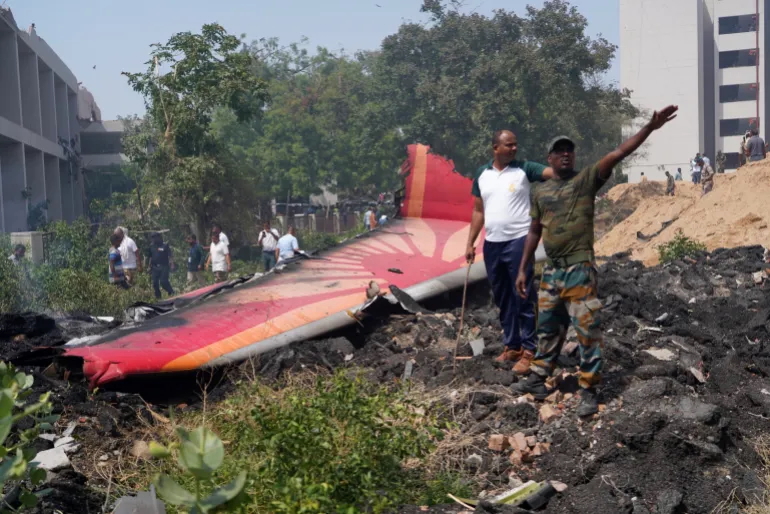 Orang-orang berdiri di dekat puing-puing di lokasi kecelakaan pesawat di dekat Bandara Internasional Sardar Vallabhbhai Patel di Ahmedabad, Gujarat, India bagian barat, 12 Juni 2025.
