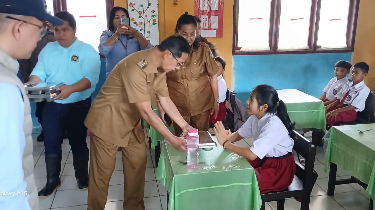Wali Kota Bitung Hengky Honadar saat memberikan paket makanan bergizi gratis kepada pelajar SD.(Dok Istimewa)