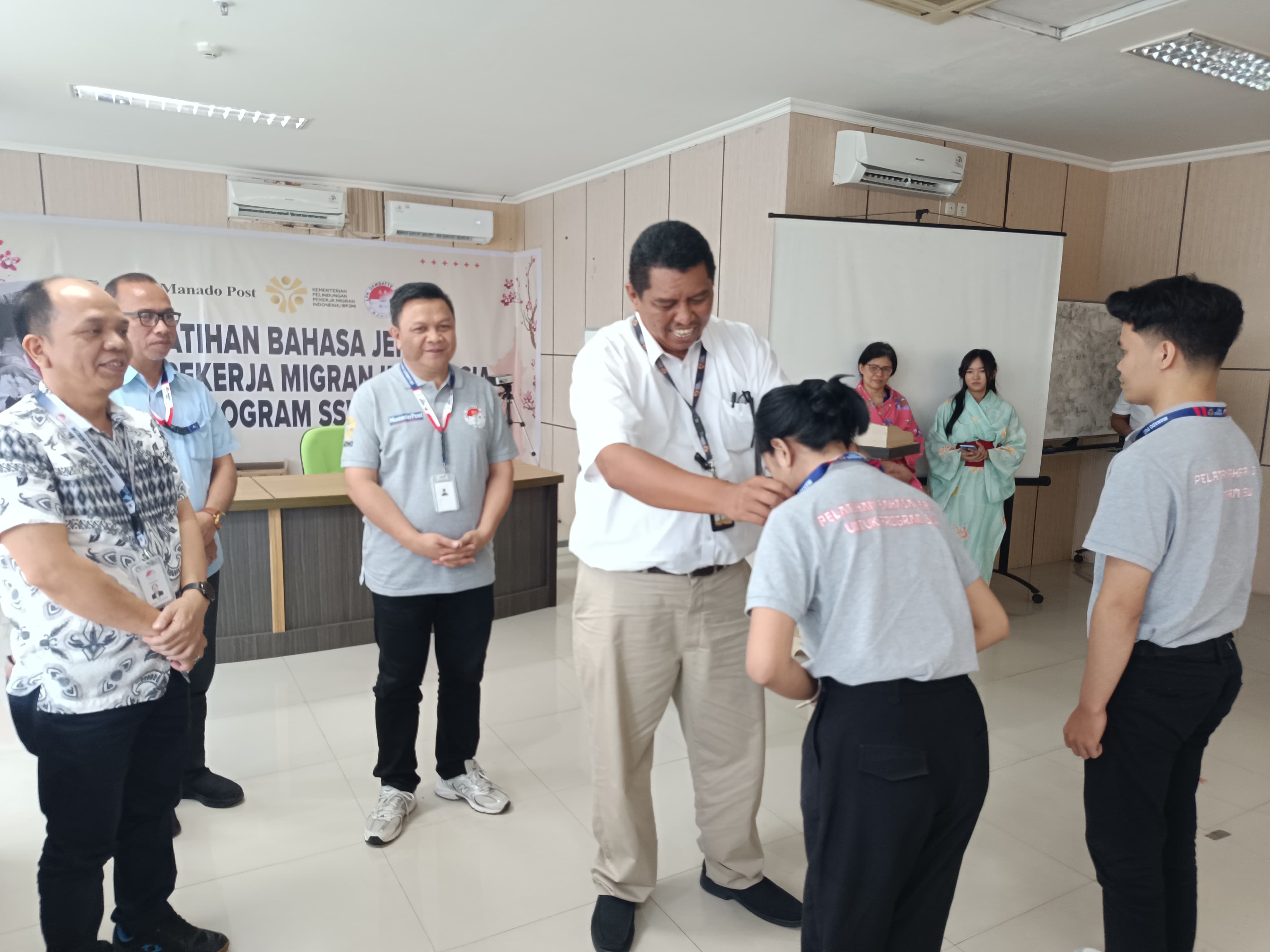 Kepala BP3MI Sulawesi Utara Syachrul Afriyadi didampingi Direktur Manado Post Tommy Waworundeng secara simbolis mengalungkan tanda peserta pelatihan di Grha Pena