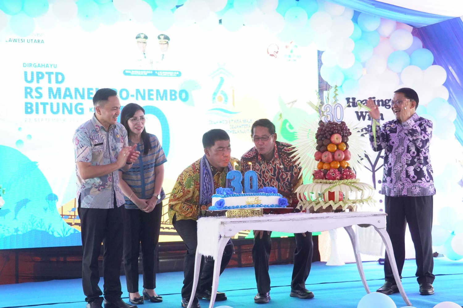 Gubernur Sulut Mayjen TNI (Purn) Yulius Selvanus dan Wali Kota Bitung Hengky Honandar kompak meniup lilin HUT ke-30 RSMN.(Dok Istimewa)
