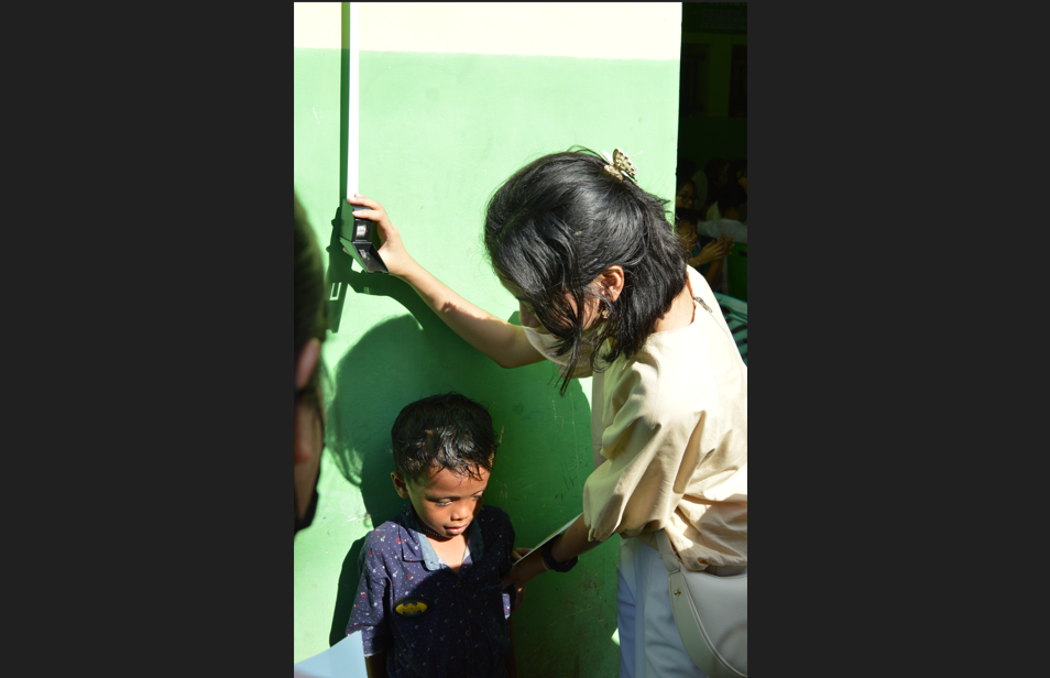 Seorang mahasiswa kedokteran memantau pertumbuhan anak saat kegiatan sosial SPARK Campaign 2025 di Manado, sebagai bagian dari edukasi dan pemeriksaan kesehatan anak.