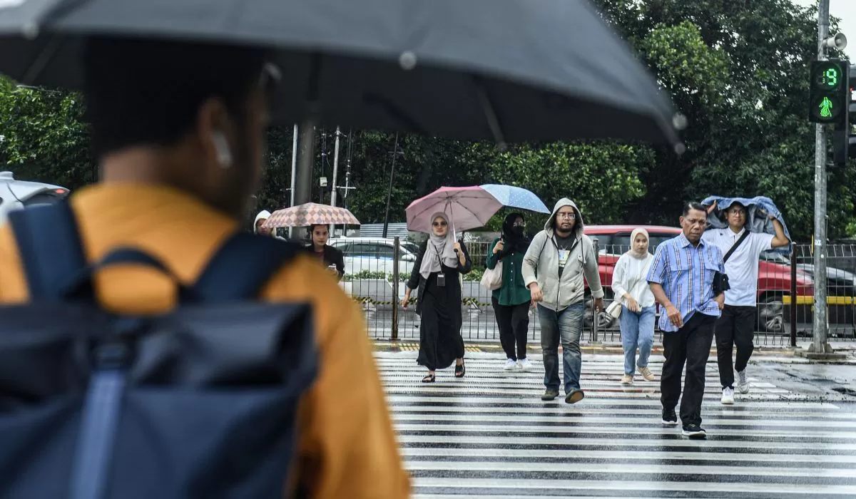 Sejumlah warga menyeberang jalan saat hujan di Jakarta, Jumat (15/3/2024) (Muhammad Adimaja/ANTARA)
