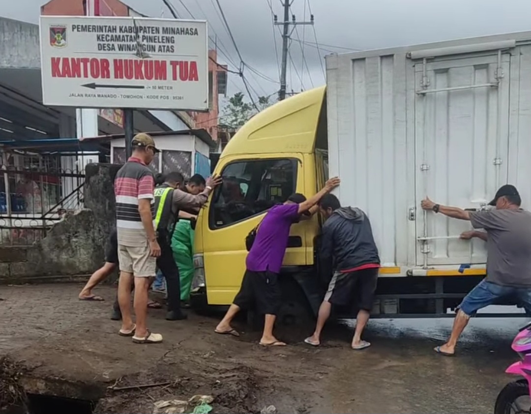 Warga berupaya mengeluarkan mobil yang terperosok di dalam lubang bekas galian pemasangan pipa air.