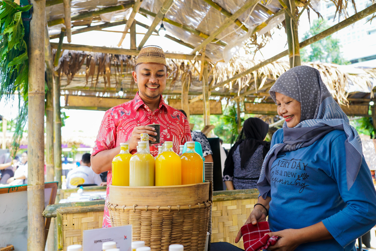 Foto Founder & CEO Amartha, Andi Taufan Garuda Putra saat mengunjungi booth UMKM jamu tradisional milik Ibu Wagini