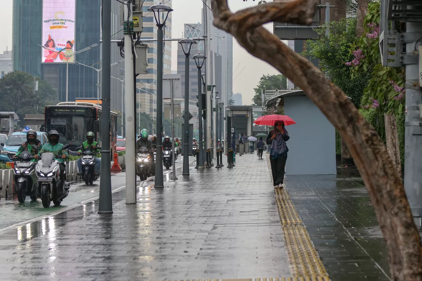 Sejumlah pejalan kaki melindungi diri dengan payung dan jaket saat hujan turun di sekitar Bundaran HI, Jakarta, Selasa (28/10/2025). (Hanung Hambara/Jawa Pos)									 