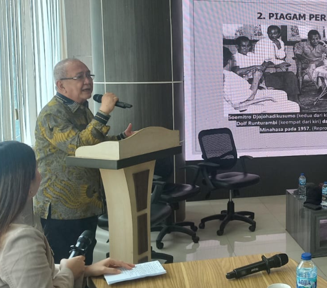 Ketua Majelis Keluarga Besar Permesta Philip Pantouw dengan latar belakang LED yang menampilkan pertemuan Prof Sumitro Djojohadikusumo dengan Ventje Sumual dan petinggi Permesta lainnya di Kinilow 