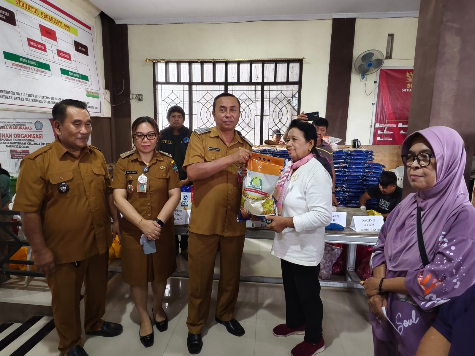 Pasar Murah-Kepala Dinas Perdagangan Minahasa Utara Maximelian Tapada saat melayani masyarakat yang datang ke Pasar Murah di Desa Warukapas.  