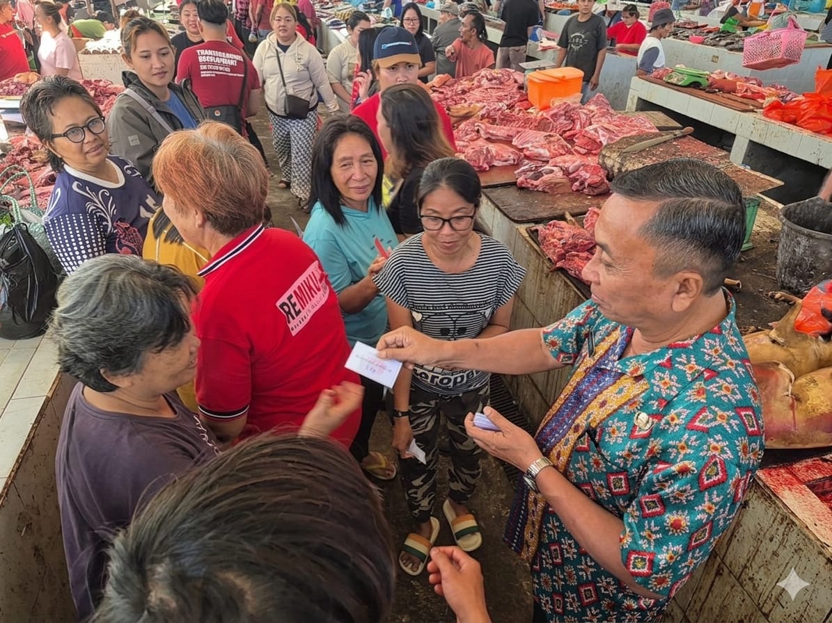Kepala Dinas Perdagangan Minut, Maximilian Tapada saat membagikan kupon subsidi daging babi kepada masyarakat yang ada di Pasar Airmadidi