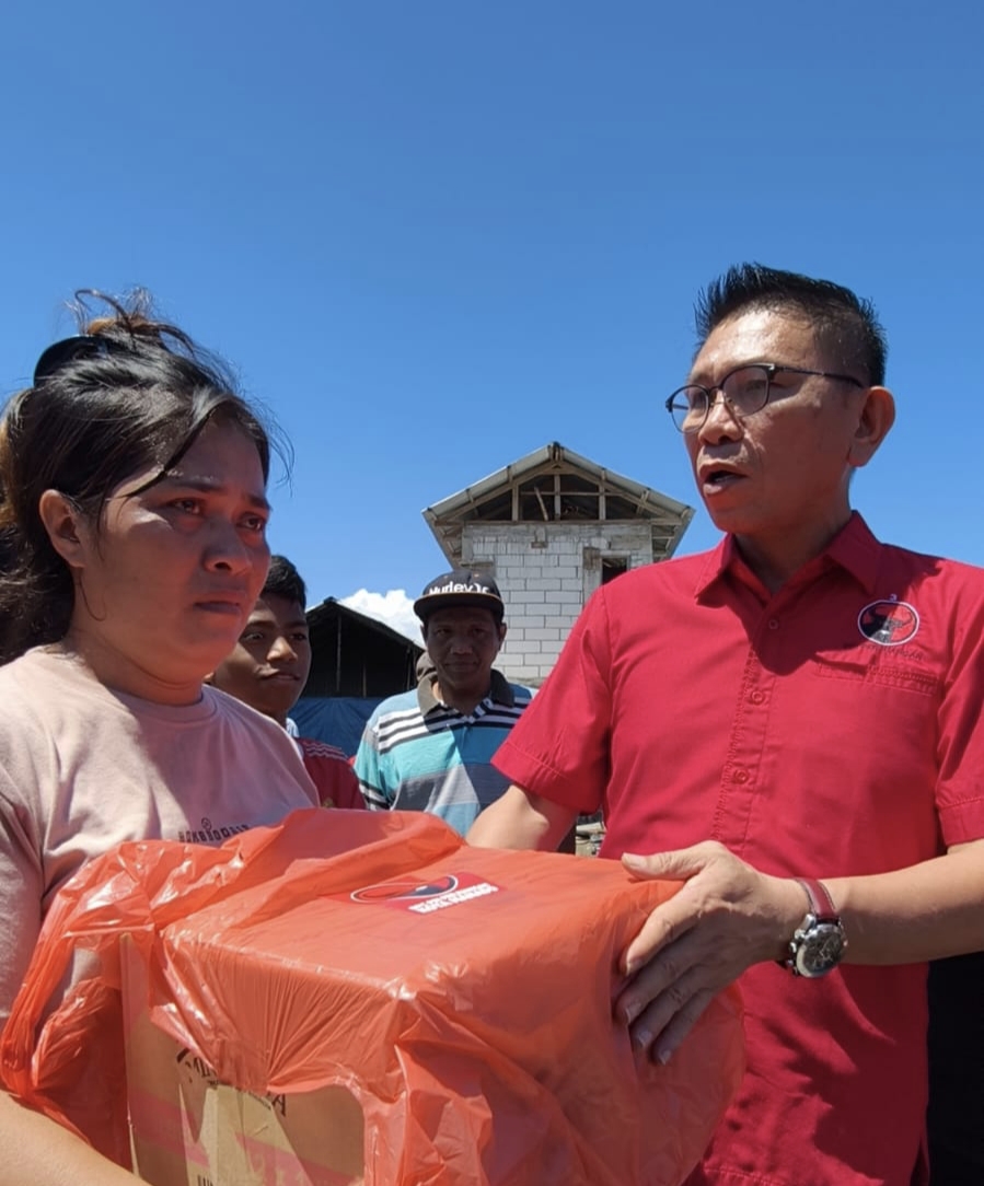 Salah seorang warga korban kebakaran menangis ketika menerima bantuan yang diserahkan oleh Sekretaris DPC PDIP Manado, Kamis (26/3)