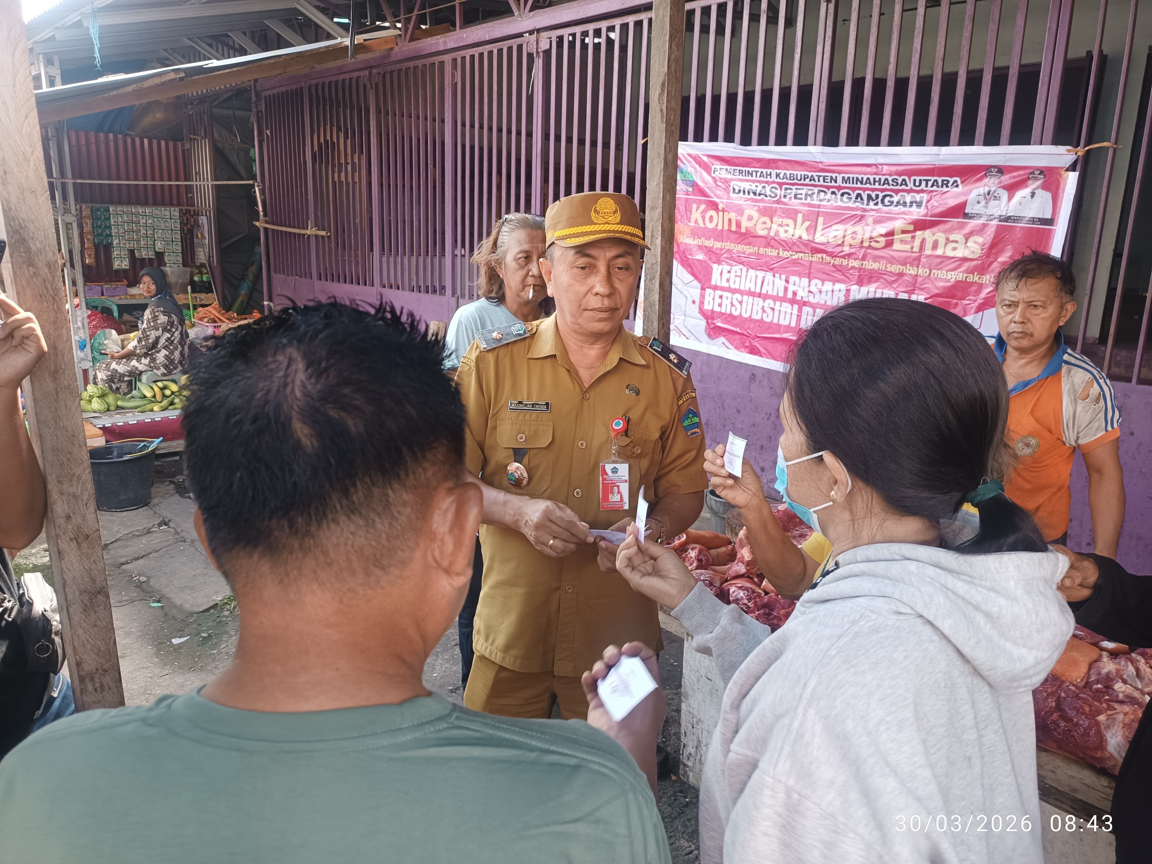 Pasar Murah-Kepala Dinas Perdagangan Minut, Sinpersli Maximelian Tapada saat membagikan kupon kepada masyarakat Likupang.