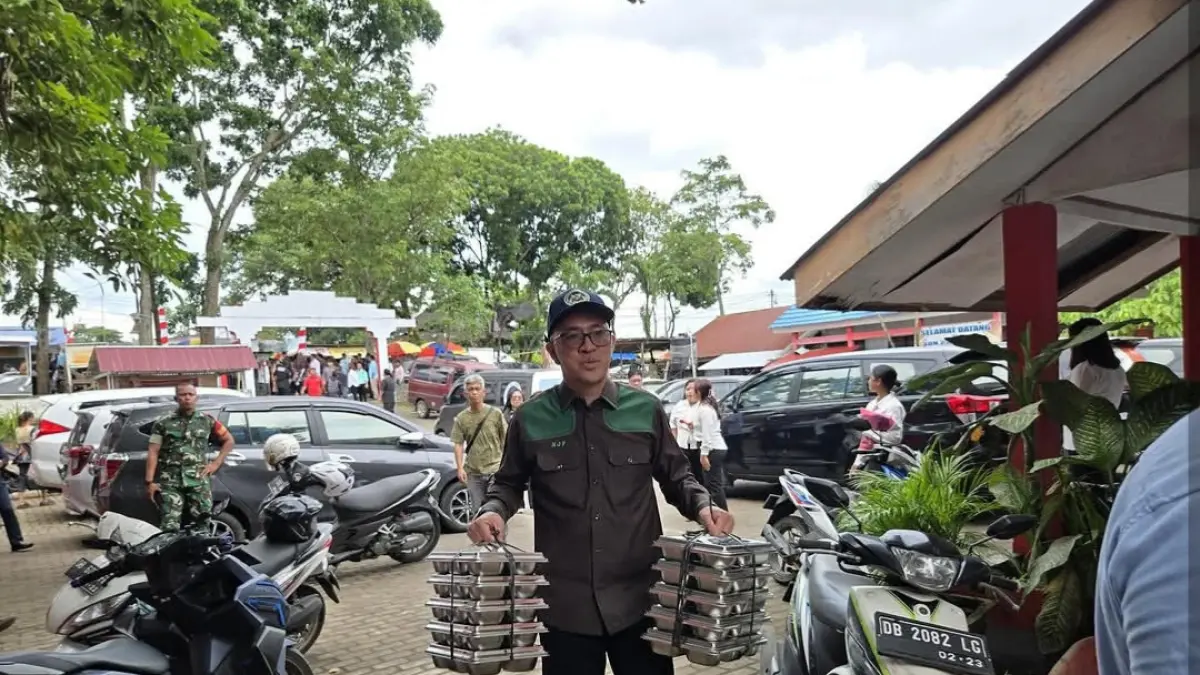 GURITA BISNIS: Melky Jakhin Pangemanan saat menenteng rantang MBG dalam satu kegiatan.