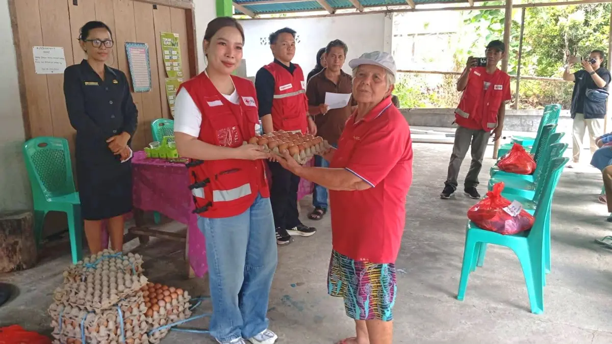 SALURKAN: Ketua PMI Minahasa Sarah Dondokambey saat menyalurkan bantuan kepada salah satu warga terdampak banjir rob, Sabtu (2/5/2026).