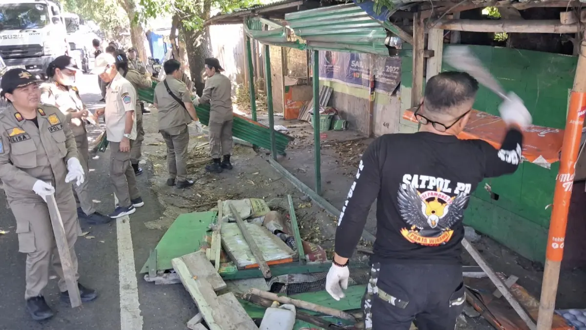 Personil Satpol PP Pemkab Minut saat melakukan pembongkaran bangunan liar di bahu jalan. 
