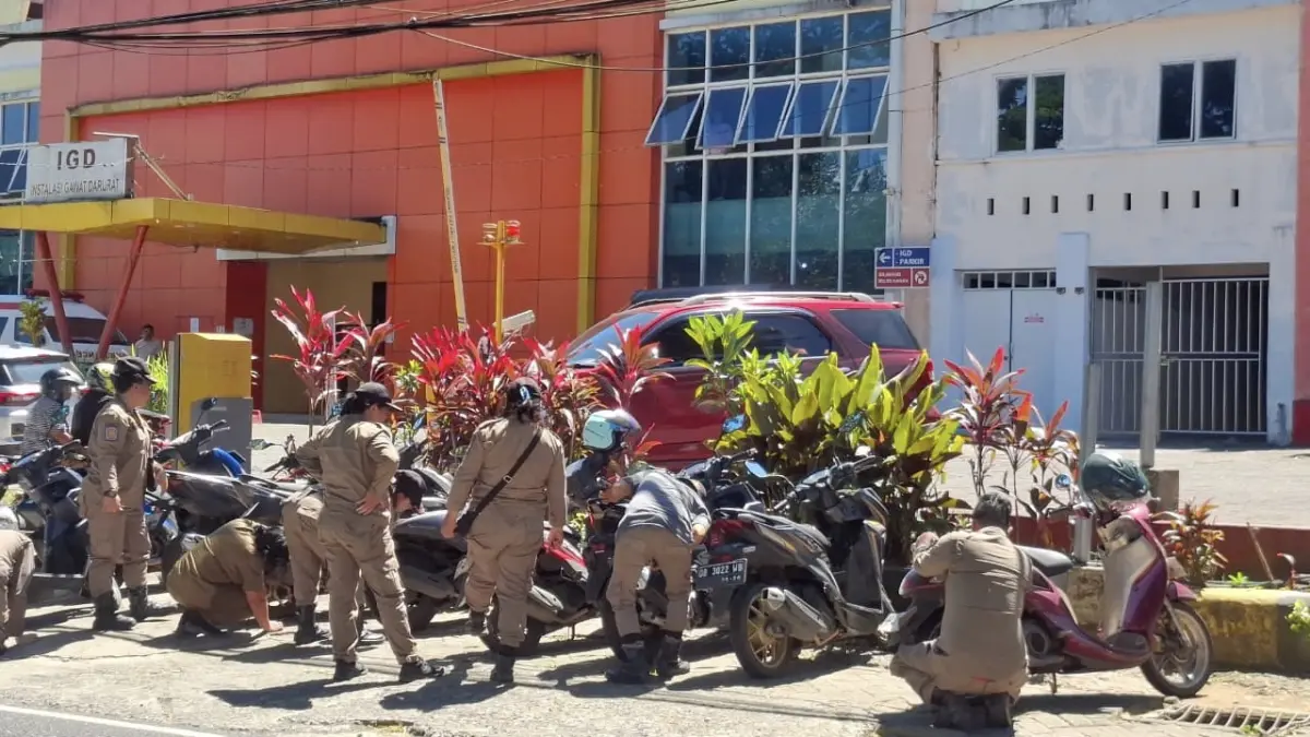 Tegakan Aturan-Personil Satpol-PP Minut saat melakukan penggembosan ban kendaraan yang parkir di depan RSUD Walanda Maramis. 
