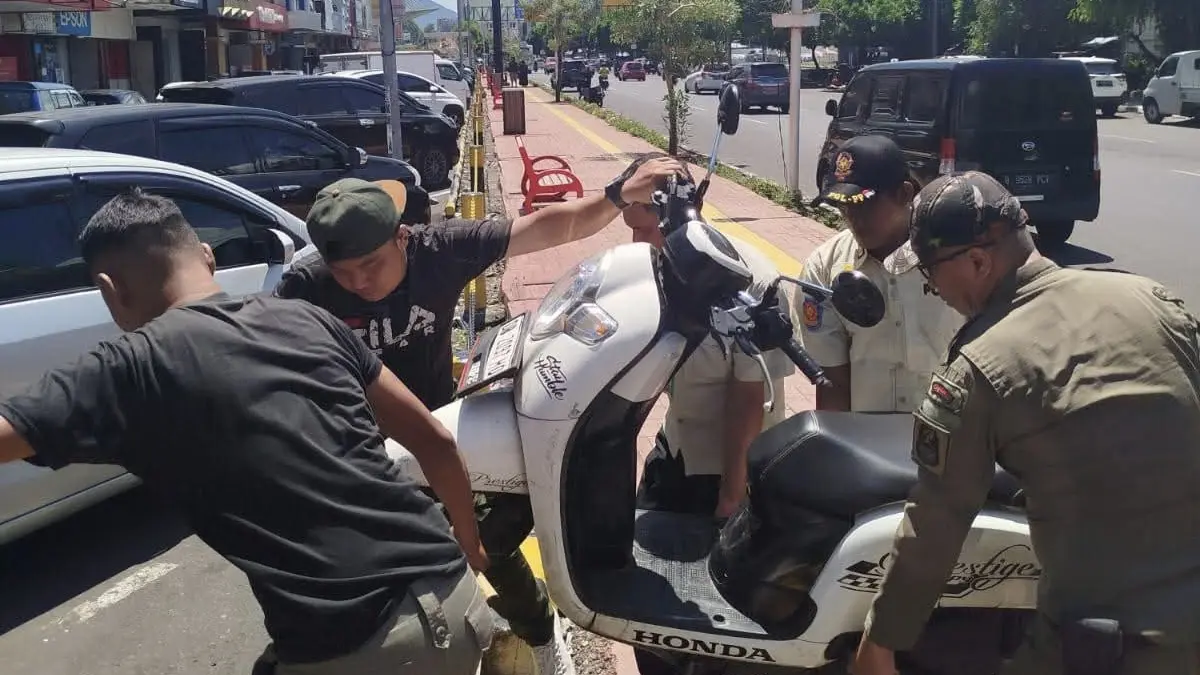 TEGAS: Personel Satuan Polisi Pamong Praja Kota Manado saat menertibkan kendaraan yang parkir di trotoar sepanjang Jalan Piere Tendean