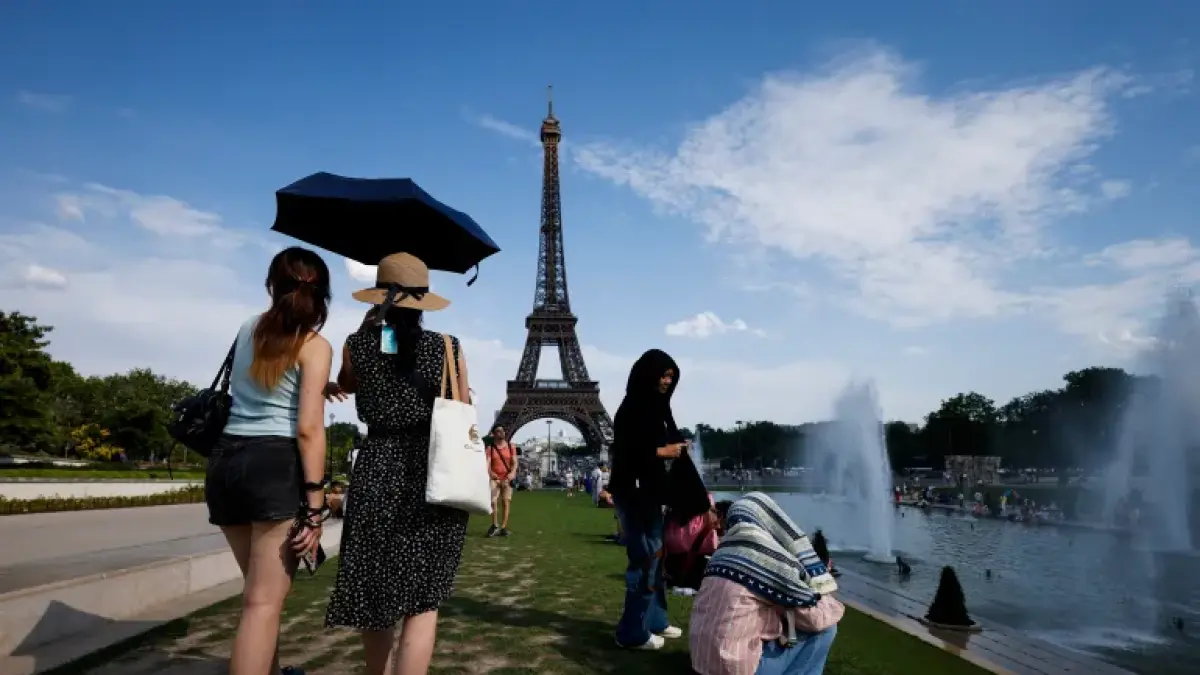 Warga berteduh dari sengatan panas di dekat air mancur Trocadero berlatar Menara Eiffel, Paris, Prancis. (doc: Yoan Valat/EPA)