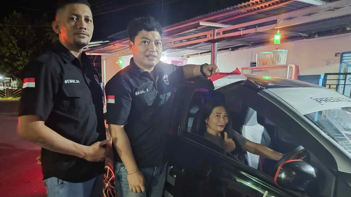 Pengurus organisasi Kepemudaan Predator, Hendry Manumpil dan Ragil membagikan bendera merah putih gratis kepada pengendara di pusat kota Tahuna, Sabtu (1/8/26).
