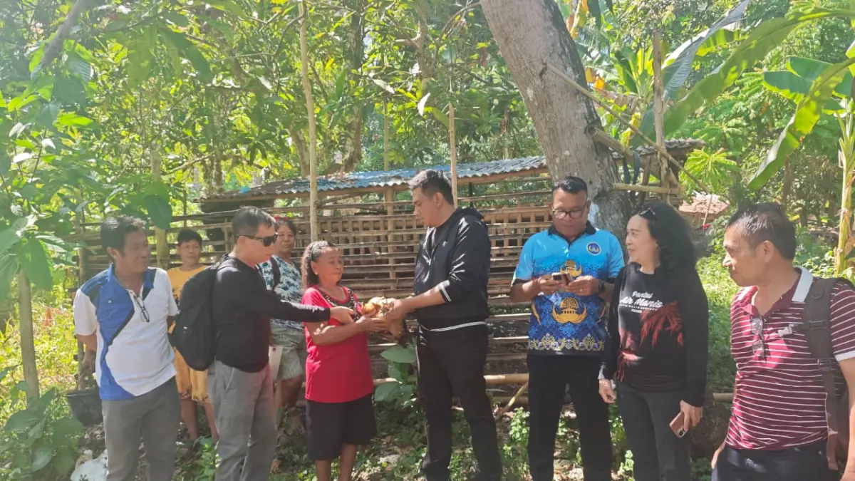 Kepala Dinas Pangan Minahasa Utara Asriyadi Lalompoh saat menyeragkan secara simbolis bantuan Bibit ayam kepada masyarakat Desa Gangga 1.
