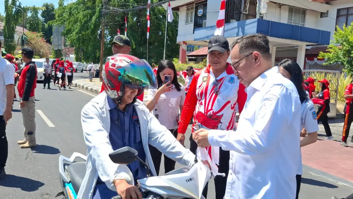 NASIONALIS: Wakil Wali Kota Richard Sualang saat membagikan bendera merah putih kepada pengendara di kompleks Kantor Wali Kota Manado, Rabu (5/8)