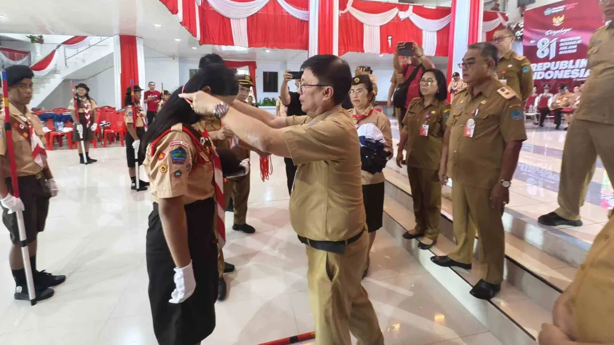 Sekretaris Daerah Minahasa Utara Novly Wowiling saat memakaikan tanda peserta dalam pelepasan kontingen Kwartir Cabang (Kwarcab) Gerakan Pramuka Minahasa Utara yang akan mengikuti Jambore Nasional. 
