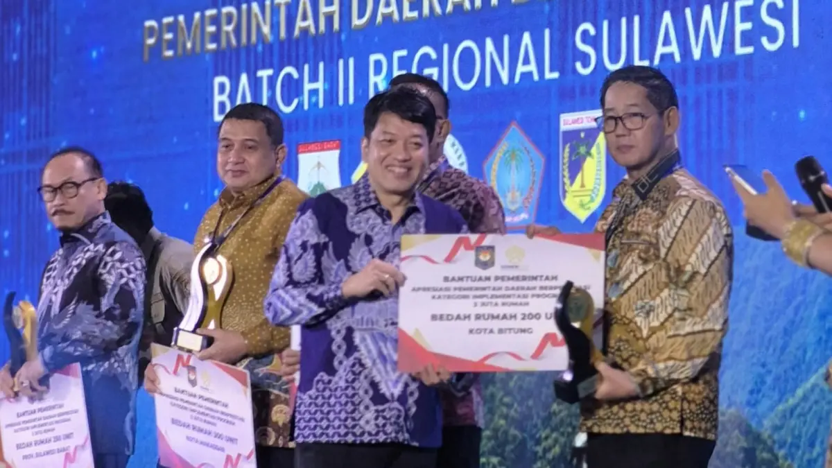 Wakil Kepala BPS RI Sonny Harry Budiutomo Harmadi menyerahkan penghargaan Terbaik III Program 3 Juta Rumah kepada Wali Kota Bitung Hengky Honandar.(Dok Istimewa)
