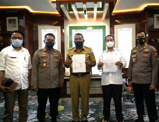 Wakil Bupati Gorontalo Utara, Thariq Modanggu, dan Bupati Bolaang Mongondow Utara, Depri Pontoh, saat foto bersama dengan memegang dokumen kesepakatan bersama tentang larangan mudik. Foto: istimewa.