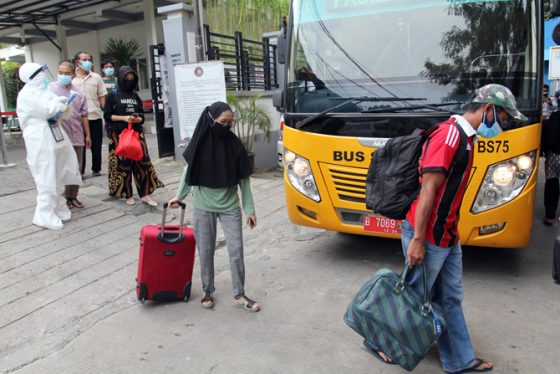 Petugas medis mengarahkan warga yang berstatus Orang Tanpa Gejala (OTG) virus korona untuk masuk ke dalam bus tujuan Wisma Atlet Kemayoran (jpc)