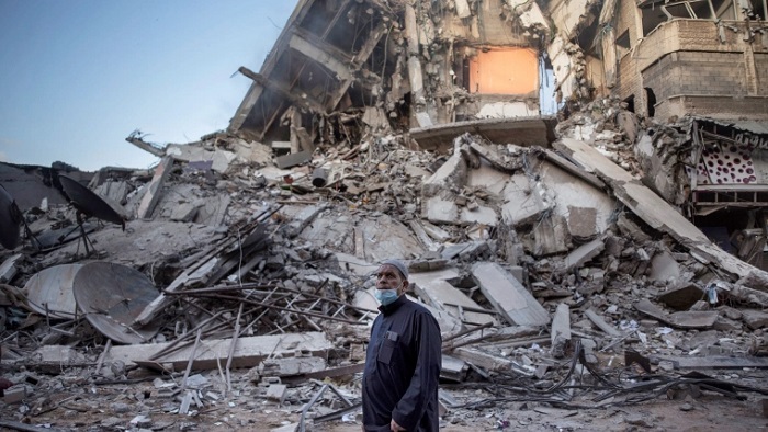 Seorang pria Palestina melihat kehancuran sebuah bangunan yang terkena serangan udara Israel di Kota Gaza. (Khalil Hamra/AP/Aljazeera)