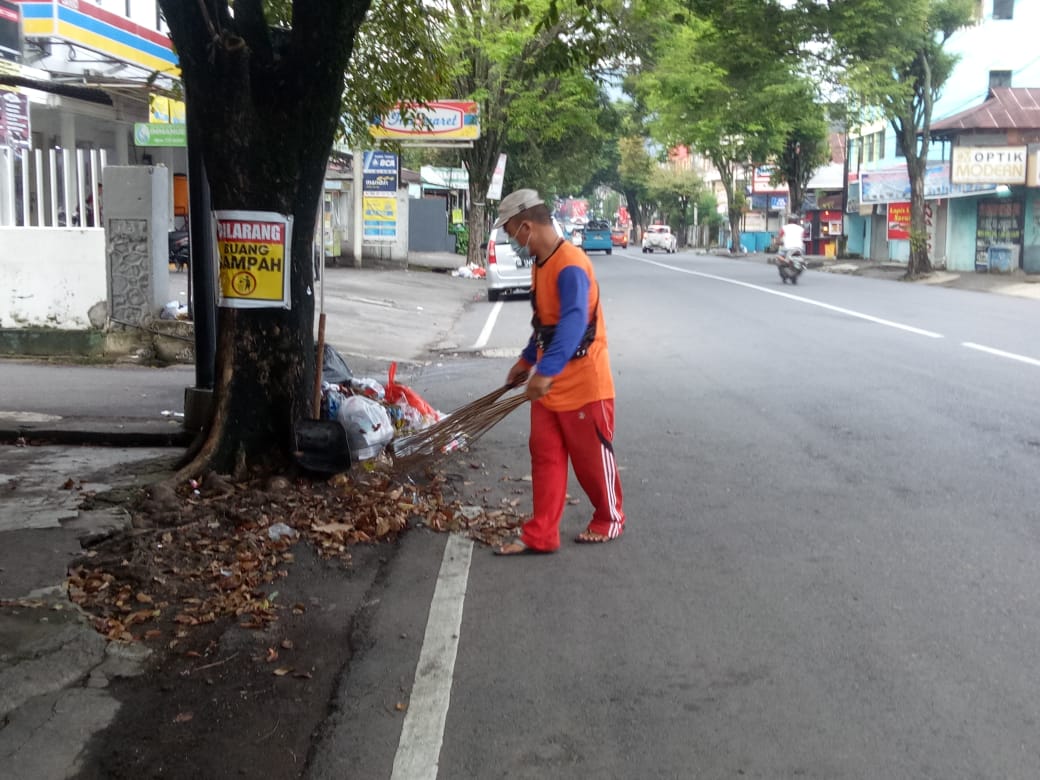 Salah satu petugas kebersihan Kecamatan Sario melakukan pembersihan sampah organik di jalan.