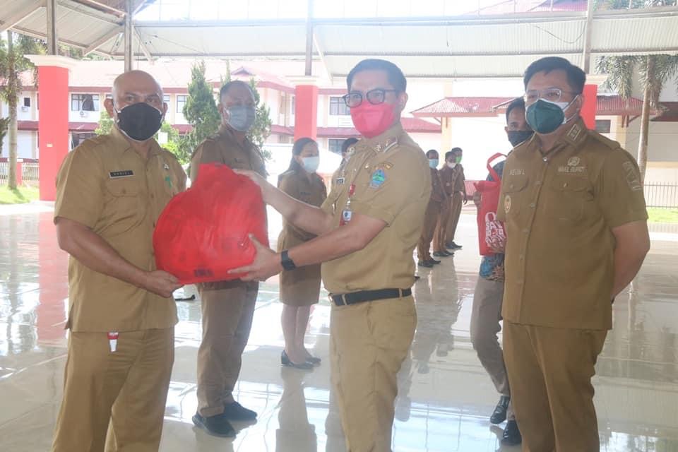 Bupati Minut Joune Ganda menyerahkan bantuan secara simbolis kepada para camat untuk diserahkan bagi warga yang membutuhkan.