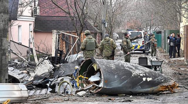 HANCUR LEBUR: Petugas mengumpulkan puing-puing pesawat yang jatuh dan menabrak sebuah rumah di Kiev kemarin (25/2). (AFP)