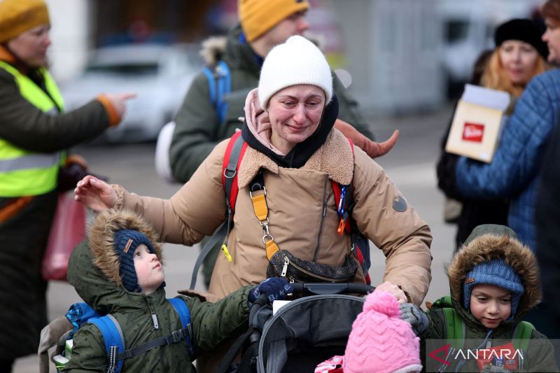 Warga Ukraina membawa anak-anaknya melintasi perbatasan di Siret, Rumania, Senin (28/2/2022). (ANTARA FOTO/REUTERS/Stoyan Nenov/foc) 