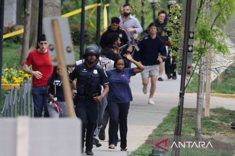 Petugas Polisi Metropolitan Washington, D.C. berlari dengan warga sipil sementara seorang petugas terus mengarahkan senjatanya ke gedung terdekat saat polisi mengevakuasi warga ke tempat yang aman di lokasi penembakan yang terjadi di dekat Edmund Burke Mi
