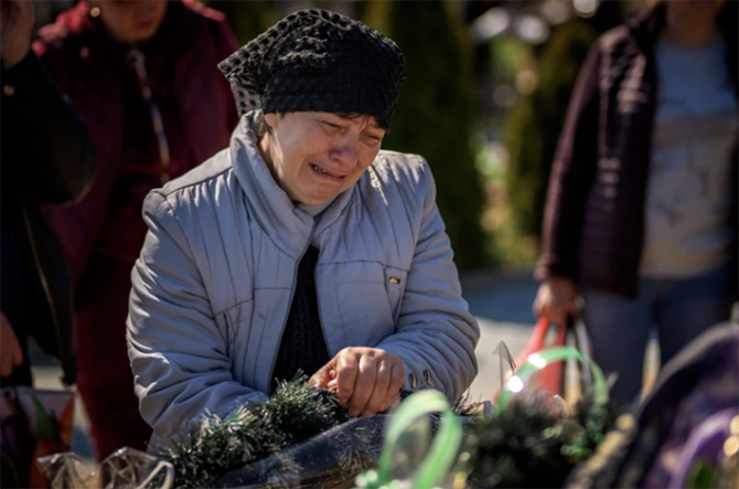 Ibu dari Oleksandr Mozheiko, 31, seorang prajurit Pertahanan Teritorial Irpin yang terbunuh oleh tentara Rusia, menangis di makamnya di pemakaman Irpin, di pinggiran Kyiv, 1 Mei 2022 (Emilio Morenatti/AP Photo)