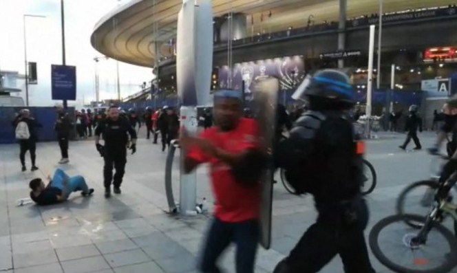 Seorang polisi mengadang pendukung Liverpool yang memaksa masuk ke dalam Stade de France sebelum laga final Liga Champions antara Liverpool dan Real Madrid. (Maryam El Hamouchi/AFP)