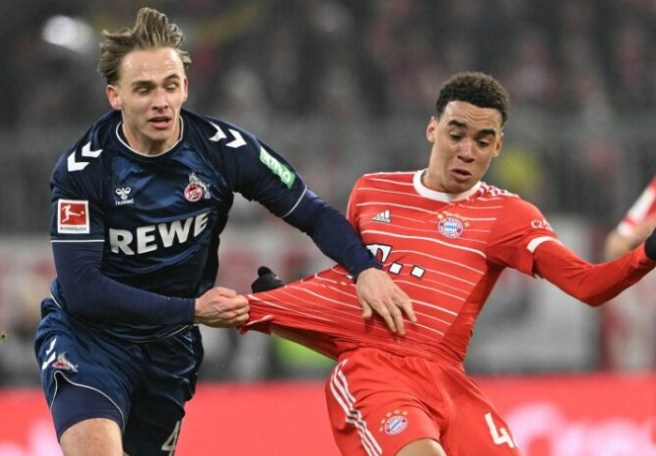 Gelandang Koln Mathias Olesen (kiri) berduel memperebutkan bola dengan gelandang Bayern Muenchen Jamal Musiala pada pertandingan Liga Jerman yang dimainkan di Stadion Allianz Arena, Munich, Rabu (25/1/2023). (ANTARA/AFP/CHRISTOF STACHE)