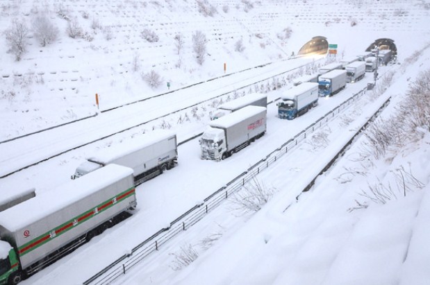 Truk-truk terjebak salju tebal di jalan tol Shin-Meishin, Yokkaichi, Jepang. (AFP)
