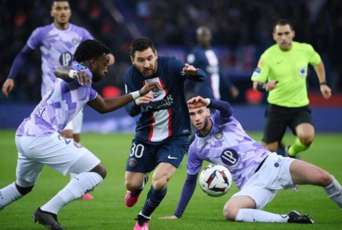 Lionel Messi berusaha melewati penjagaan bek Toulouse FC Warren Kamanzi dalam journee ke-22 Ligue 2 di Parc des Princes kemarin (5/2) dini hari WIB. (FRANCK FIFE/AFP )