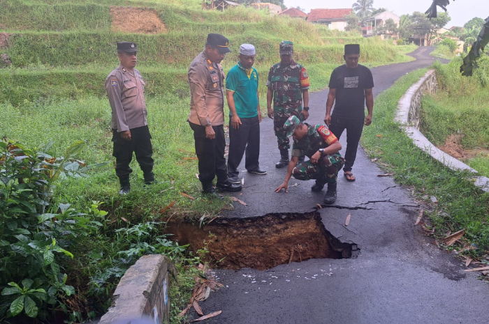 Petugas memeriksa kondisi jalan jembatan penghubung dua desa di Kecamatan Nanggung, Kabupaten Bogor yang ambles.