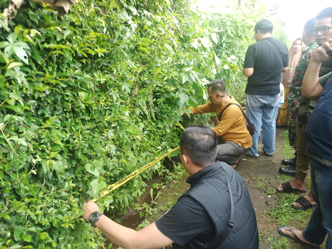 Petugas memasang garis polisi di selokan tempat ditemukannya jasad bayi di Desa Tugu Selatan, Kecamatan Cisarua, Minggu (5/5/2024).