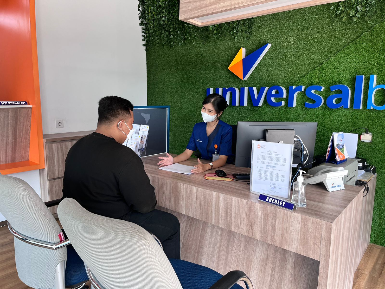 Karyawan Bank Universal BPR kantor cabang Bogor menjelaskan tabungan Universal Arisan kepada nasabah.